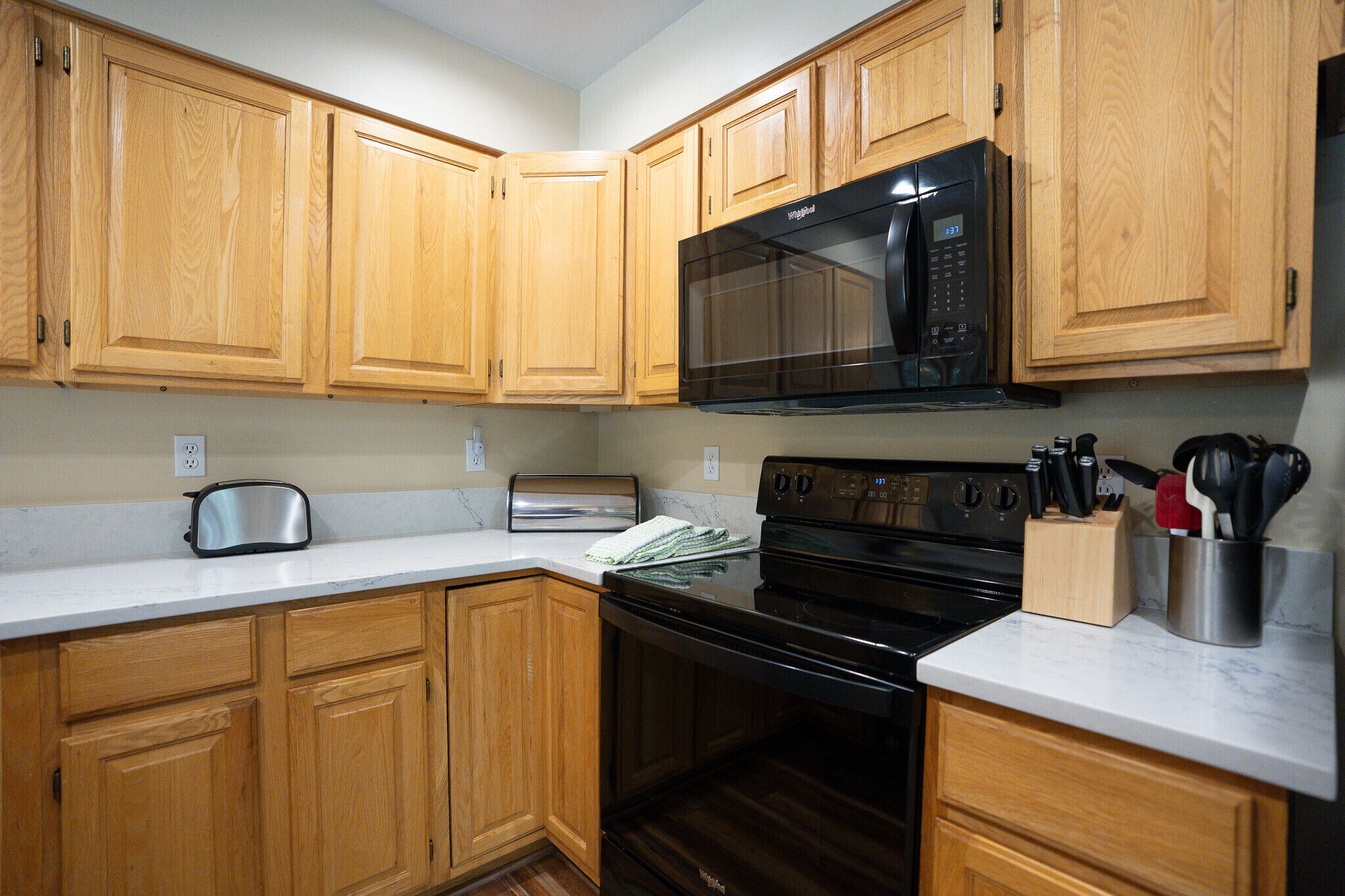 A kitchen with wooden cabinets, a microwave, a toaster, and a stove.