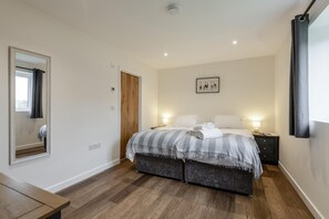 Ein Schlafzimmer mit einem Bett, Nachttischen, einem Spiegel und einer Tür.