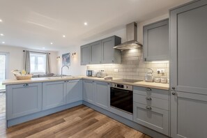 Eine moderne Küche mit grauen Schränken, einem eingebauten Backofen und einer Mikrowelle.