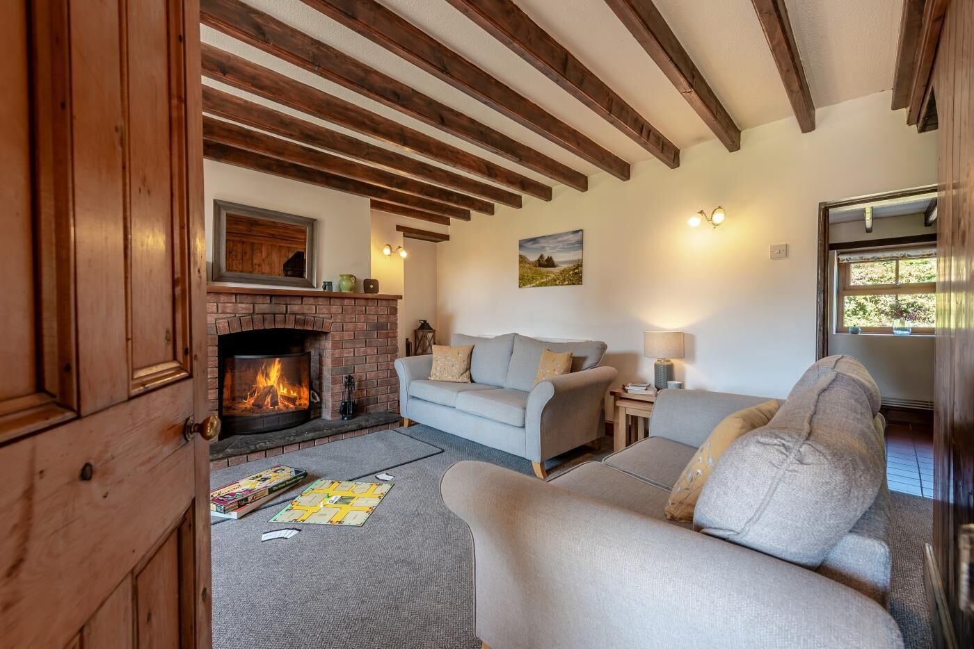 Un salon chaleureux avec une cheminée, un canapé, un fauteuil et une petite table sur laquelle se trouve une lampe.
