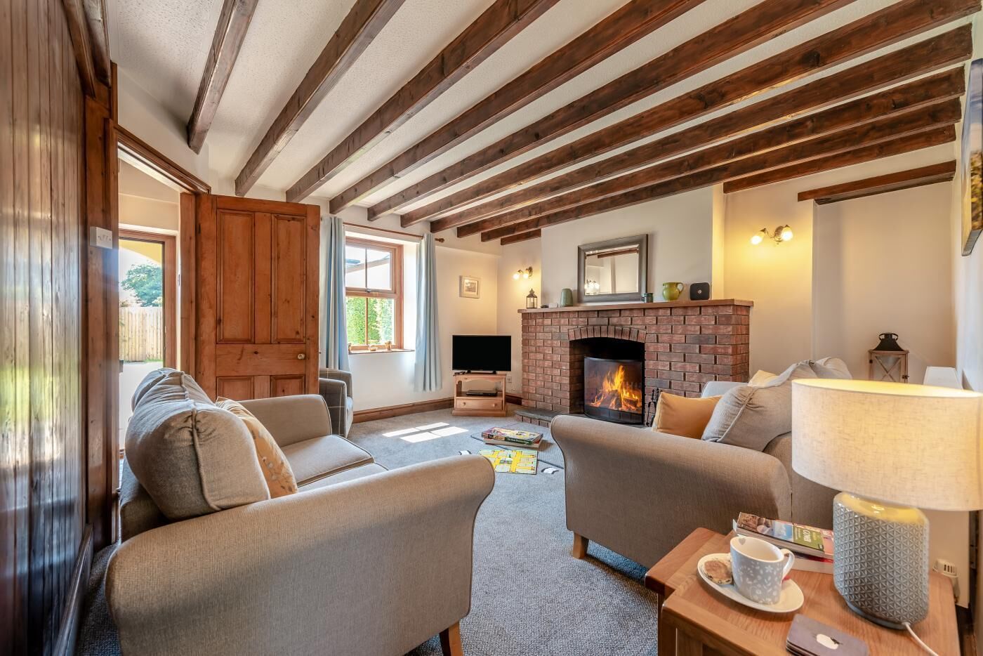 A cozy living room with exposed wooden beams, a fireplace, and comfortable seating.