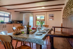 A dining area with a table set for four, a bottle of wine, and a vase with flowers. - 3 Bed in Parkmill (oc-t36336) (Parkmill)