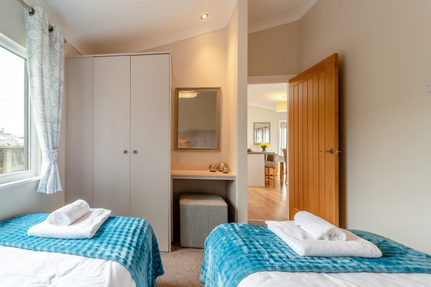 Une chambre avec deux lits, une armoire, un bureau et un miroir.