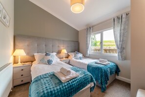 A bedroom with two beds, a window with curtains, and a headboard. - 2 Bed in Glenluce (oc-c36927) (Glenluce)