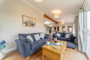 A modern living room with two sofas, a coffee table, and a dining area. - 2 Bed in Glenluce (oc-c36927) (Glenluce)