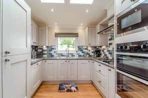 A modern kitchen with white cabinetry, a tiled backsplash, a window, and a built-in oven. - 2 Bed in Glenluce (oc-c36927) (Glenluce)