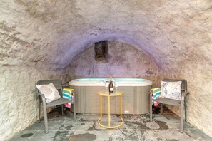 A hot tub with two chairs and a table in a cave-like setting. - 2 Bed in Tenby (oc-b41400) (Tenby)