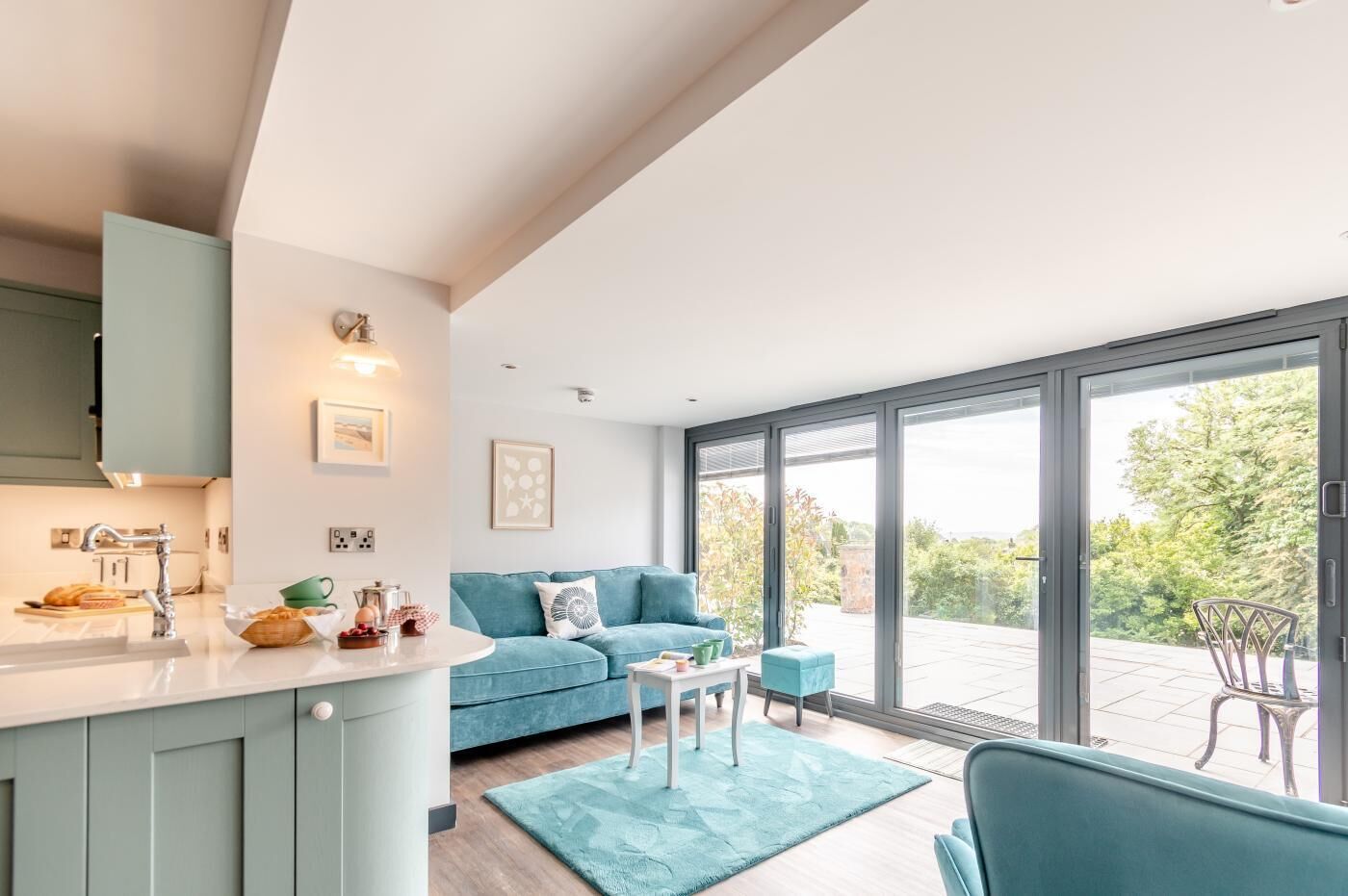 Ein modernes Wohnzimmer mit einer Couch, einem Couchtisch und Blick ins Freie durch große Schiebeglasfenster.
