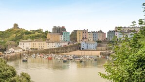 A coastal town with historic buildings, a harbor with boats, and a hilltop structure. - 2 Bed in Tenby (oc-b41400) (Tenby)