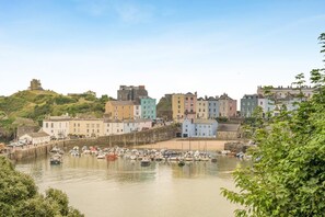 A coastal town with historic buildings, a harbor with boats, and a hilltop structure. - 2 Bed in Tenby (oc-b41400) (Tenby)