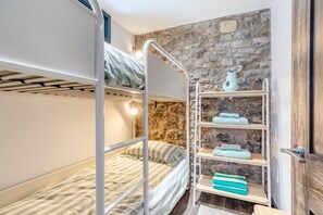 A bunk bed with a stone wall and a shelf with towels. - 2 Bed in Tenby (oc-b41400) (Tenby)