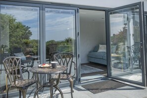 A glass-enclosed patio with a round table and chairs, a sofa, and a view of the outdoors. - 2 Bed in Tenby (oc-b41402) (Tenby)