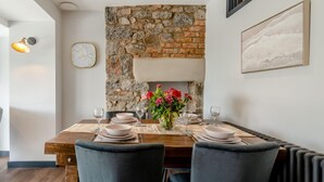 A dining area with a stone wall, a clock, and a framed picture on the wall. - 2 Bed in Tenby (oc-b41402) (Tenby)