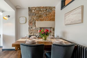 Uma sala de jantar com parede de pedra, um relógio e um quadro pendurado na parede.