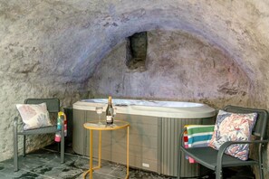A hot tub with two chairs and a table in a stone-walled alcove. - 2 Bed in Tenby (oc-b41402) (Tenby)