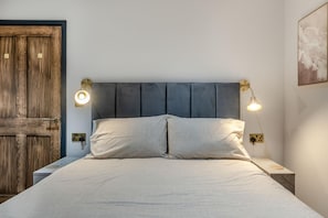 A bed with a headboard, two bedside lamps, and a wooden door. - 2 Bed in Tenby (oc-b41402) (Tenby)