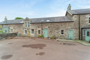 A stone building with multiple doors and windows, a paved driveway, and a bicycle parked outside. - 3 Bed in Thankerton (oc-t38220) (Thankerton)