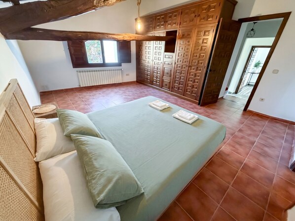 A bedroom with a bed, pillows, a radiator, and a wardrobe.
