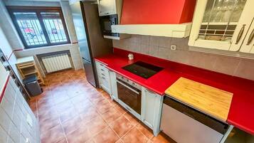 A compact kitchen with a red countertop, a built-in oven, and a dishwasher.
