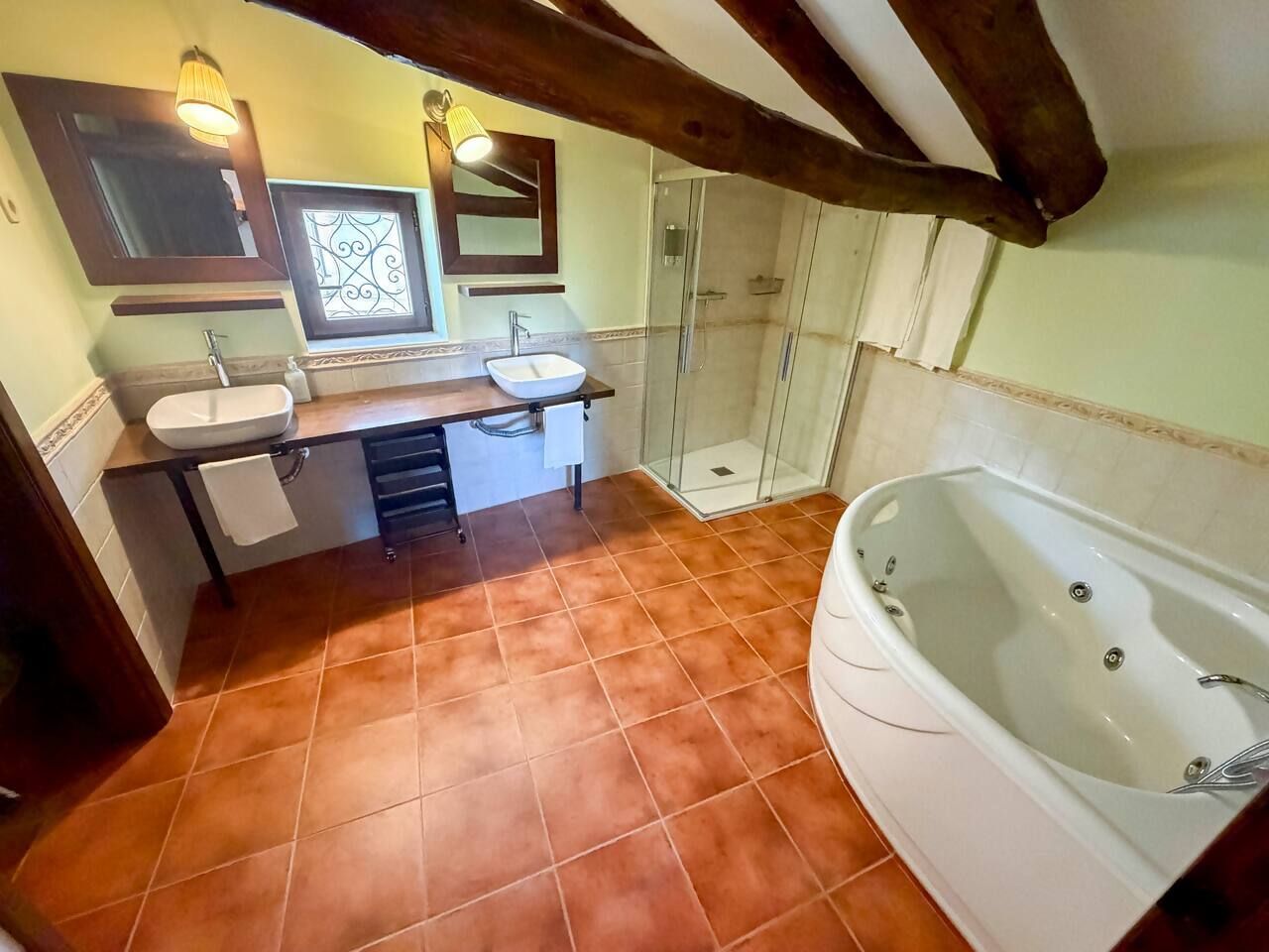 A bathroom with a bathtub, two sinks, a shower, and a tiled floor.