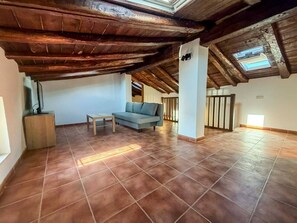 A spacious room with a high ceiling, a sofa, a small table, and a skylight.