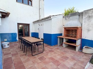 An outdoor patio with a brick table and chairs, a brick oven, and a door leading to an interior space.