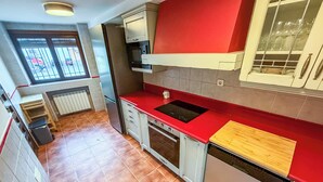 Eine Küche mit roter Arbeitsplatte, einem eingebauten Backofen und einem Geschirrspüler.