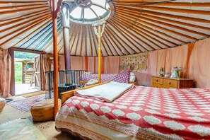 A traditional yurt with a bed, a wooden chest, and a hanging tapestry.