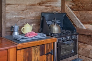 A compact kitchenette with a stove, oven, and a coffee maker.