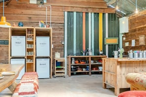 A rustic kitchen with wooden cabinets, a refrigerator, and a dining table with a bench.