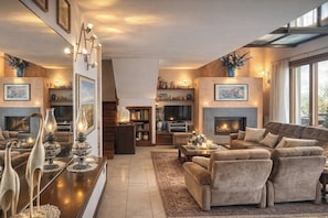 Ein geräumiges Wohnzimmer mit Kamin, bequemen Sitzmöglichkeiten und einem Fernseher.