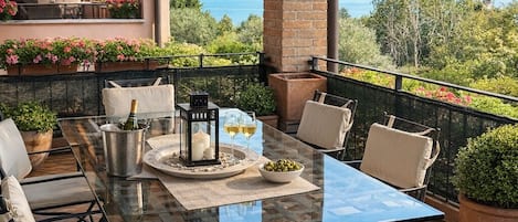 Eine Terrasse im Freien mit einem Glastisch, Stühlen und Blumentöpfen.