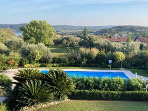 Ein Pool, umgeben von üppiger Vegetation mit Blick auf eine Stadt in der Ferne.