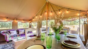 A tented dining area with a table set for two, chairs, and a sofa with cushions. - 3 Bed in Newcastle Emlyn (oc-a42685) (Cwm-cou)