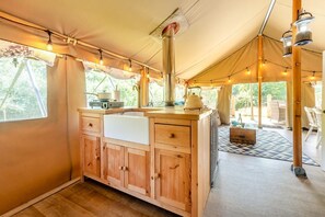 A tented accommodation with a wooden kitchenette, a central stove, and string lights. - 3 Bed in Newcastle Emlyn (oc-t42686) (Cwm-cou)