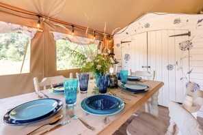 A dining table set with blue plates, glasses, and cutlery, with a vase of flowers and string lights above. - 3 Bed in Newcastle Emlyn (oc-t42686) (Cwm-cou)