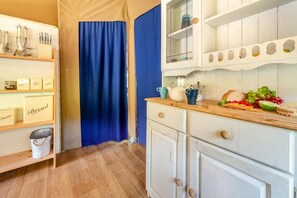 Una cocina con armarios de madera, una cortina azul y una encimera con alimentos.