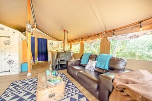 A tented accommodation with a living area featuring a sofa, a coffee table, and a kitchen area with a stove. - 3 Bed in Newcastle Emlyn (oc-t42686) (Cwm-cou)