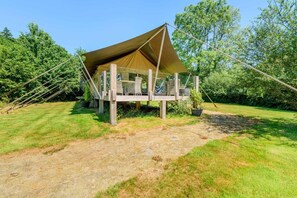 A tented structure with a wooden deck and seating area, surrounded by a grassy field and trees. - 3 Bed in Newcastle Emlyn (oc-t42686) (Cwm-cou)