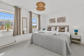 Ein Schlafzimmer mit Bett, Vorhängen, einem an der Wand befestigten Schild, einem Nachttisch und Blick ins Freie.