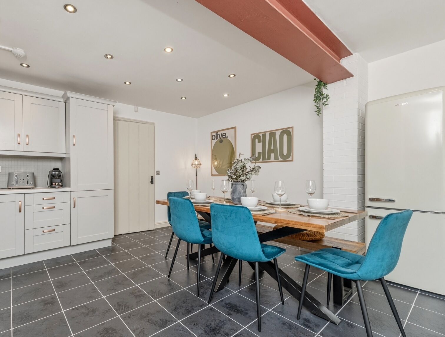 Una cocina moderna con armarios blancos, una mesa de comedor con sillas azules y una isla de cocina.