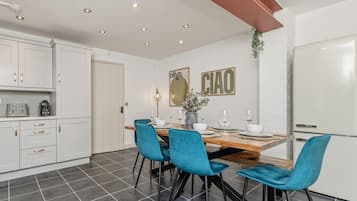 Una cocina moderna con armarios blancos, una mesa de comedor con sillas azules y una isla de cocina.