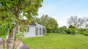 A white house with a glass conservatory, a well-maintained lawn, and a garden with various plants and trees. - 3 Bed in Sloothby (oc-i42705) (Sloothby)