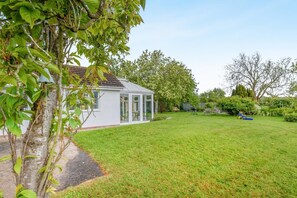 A white house with a glass conservatory, a well-maintained lawn, and a garden with various plants and trees. - 3 Bed in Sloothby (oc-i42705) (Sloothby)