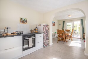 A modern kitchen with a built-in oven, a refrigerator, and a dining area with a table and chairs. - 3 Bed in Sloothby (oc-i42705) (Sloothby)
