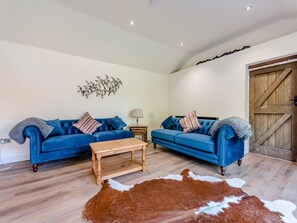 A living room with two blue sofas, a wooden coffee table, and a cowhide rug. - 2 Bed in Burton Pedwardine (oc-t42740) (Burton Pedwardine)