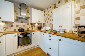 A kitchen with white cabinets, a stainless steel oven, a wooden countertop, and a tiled backsplash. - 3 Bed in Crook (oc-s43320) (Crook)