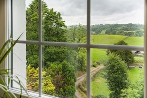 A view through a window with a rural landscape, including a green field, trees, and a building in the distance. - 3 Bed in Crook (oc-s43320) (Crook)