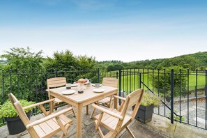 An outdoor dining area with a table and chairs, surrounded by a black metal fence, overlooking a lush green landscape. - 3 Bed in Crook (oc-s43320) (Crook)