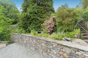 A stone retaining wall with a gravel path, surrounded by lush greenery and flowering plants. - 3 Bed in Crook (oc-s43320) (Crook)
